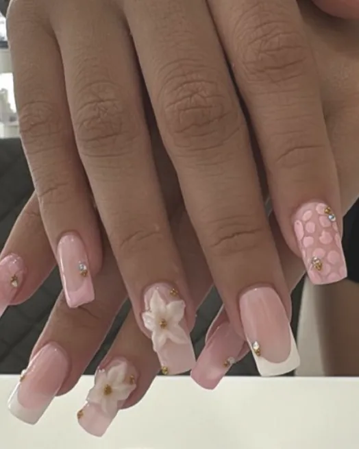 Uñas acrílicas rosa con flores 3D, francesa blanca y pedrería dorada
