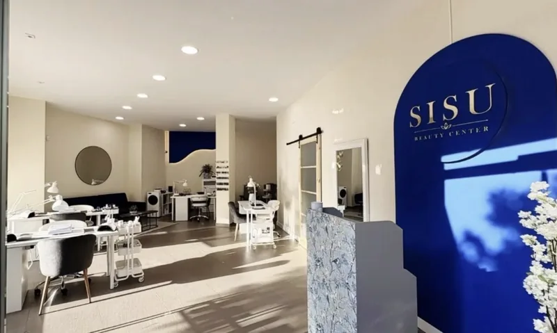Interior de SISU Beauty Center: recepción con arco azul, puestos de manicura blancos y zona de espera con luz natural
